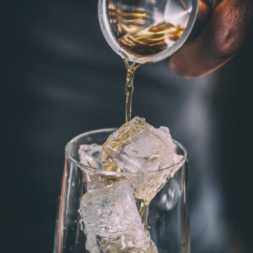 Bartender pouring alcohol in glass, close up shot